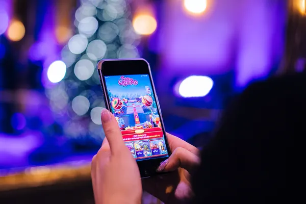 SPINARA App — Enjoy seamless gaming on your smartphone A young woman relaxing with her phone while dynamic casino elements float around her, illustrating the smooth mobile experience offered by the SPINARA app.
